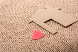 Heart shape beside paper house with a canvas background