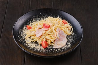 Spaghetti with ham and tomatoes sprinkled with grated parmesan