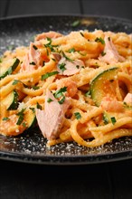 Closeup view of pasta with salmon and zuccini with grated parmesan on a plate