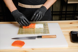 Chef puts salmon while preparing rolls