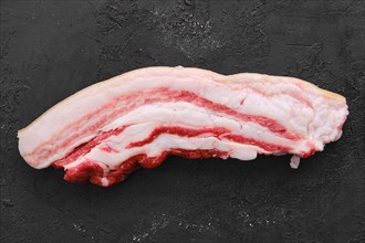 Raw fresh pork belly slice on black background