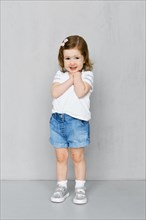 Two years old girl in white t-short and jeans shorts posing in studio