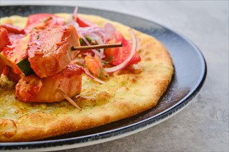 Closeup view of shashlik served on tortilla with tomato and red onion