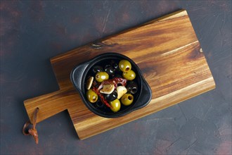 Black and green olives in Spanish on wooden plate. Top view