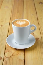 Cappuccino in ceramic cup on wooden table