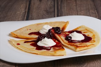 Thin pancakes with cherry and sour cream