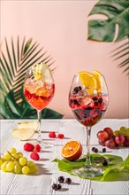 Cold sangria in wine glasses on white wooden table in morning sunlight