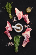 Fresh raw lamb ram shank with spice and herbs on dark background