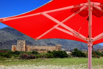 Red parasol and the fortress of Frangokastello on the south coast of the Mediterranean island