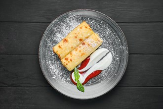 Overhead view of thin crepe with ricotta and strawberry jam on a plate