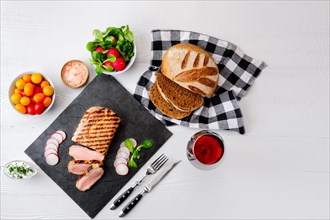 Sliced grilled roast beef with fork and knife on stone serving board. Top view with copy space for your text