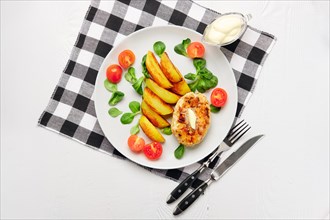 Fried chicken cutlet with potato slices served with tomato cherry and corn salad. Traditional belorussian food