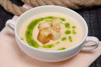 Creamy soup puree in white bowl and small pieces of fried bread toasts