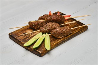 Lamb kebab on skewer on wooden board