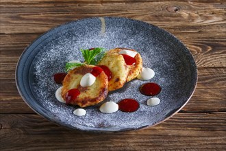 Cheese pancakes served with sour cream and strawberry jam
