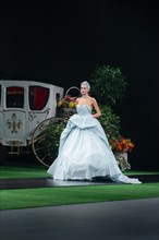 Fashion model in designers dress walking on runway decorated with Royal carriage