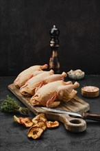 Three little raw chicken on wooden cutting board