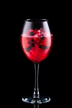 Cold sangria with forrest berries in a wine glass isolated on black background