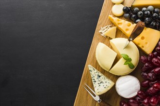 Flat lay mix of gourmet cheese and grapes on cutting board with copy space
