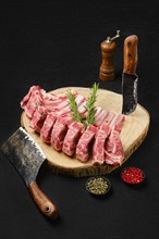 Raw fresh lamb rib roast on wooden slab and butcher cleaver