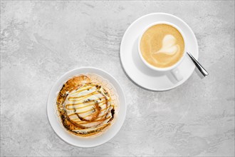 Cappuccino and rolled bun with caramel on a table