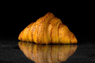 Fresh golden croissant on black table