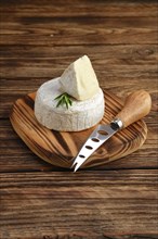 Brie cheese or camembert on woden board with knife for soft cheese