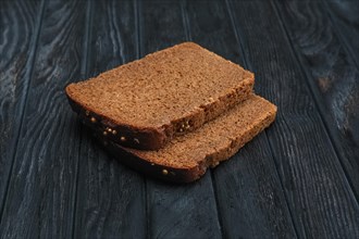 Two pieces of brown bread on dark wooden table