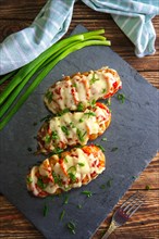 Hasselback potato with chorizo sausage covered with melted cheese baked in oven