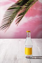 Small bottle of tonic water on white wooden table under morning sunlight