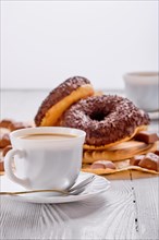 Chocolate donuts and coffee on bright wooden table