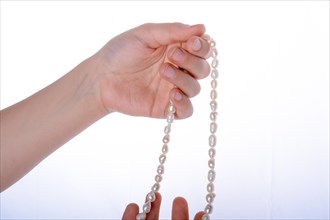 Hand holding a pearl necklace on a white background