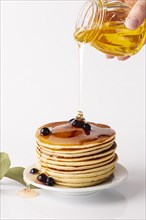 Front view honey poured pancake tower plate with blueberries