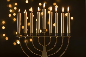 Menorah with candles near abstract garland lights
