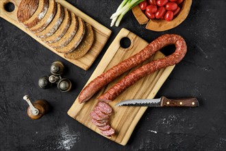 Overhead view of smoked pork sausage rings on wooden cutting board on kitchen table