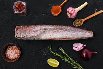 Raw hake with spice on black background
