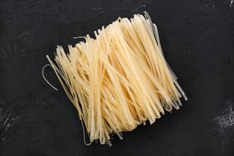 Dry rice stick noodles on black concrete background