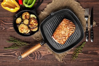 Top view of grilled striploin on grill pan and fried eggplant on wooden background