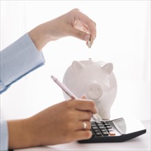 Woman s hand using calculator while inserting coin piggybank. Resolution and high quality beautiful photo