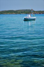 Greek fishing boat moored in blue waters of Aegean sea in harbor of near Milos island