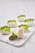 Frozen dumplings stuffed with pork meat and provencal herbs on marble serving plate