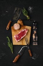Overhead view of raw strip steak boneless on dark background