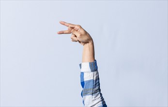 Hand gesturing the letter P in sign language on an isolated background. Man's hand gesturing the letter P of the alphabet isolated. Letter P of the alphabet in sign language
