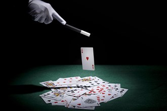 Magician performing trick playing cards with magic wand poker table