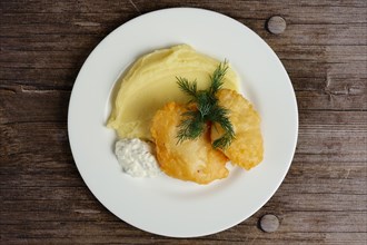 Top view of fish fillet in batter with mashed potato on wooden table