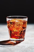 Glass with cola with ice in bright sunlight