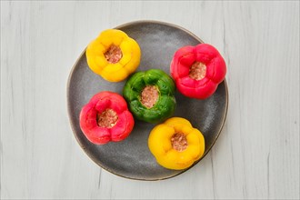 Top view of colorful bell pepper stuffed with meat and rice on white wooden table