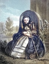 Young woman in the disguise of an old woman in an armchair in the garden