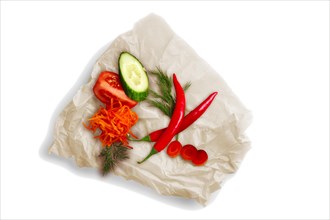 Colorful vegetables on crumpled parchment for baking isolated on white. Ingredients for salad