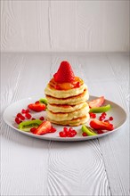 Stack of hot flapjacks served with fresh strawberries and kiwi